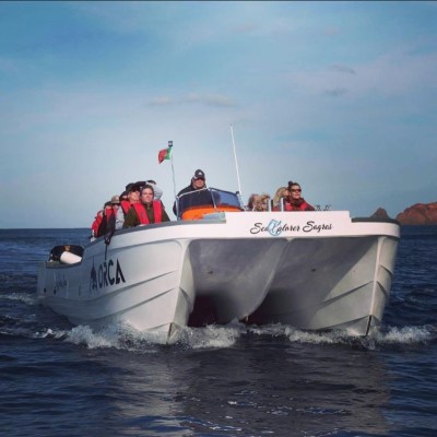 A group of people on a white boat named 'Sea Explorer Sagres' in the ocean under a clear sky.